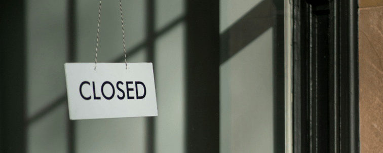 Ein Schild mit der Aufschrift "Closed", das in einem Schaufenster hängt und Insolvenz symbolisieren soll.