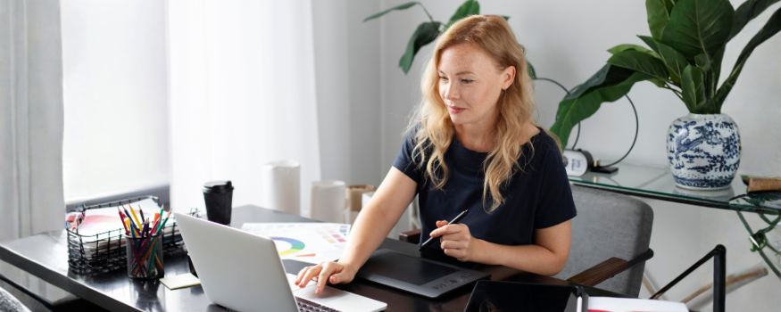 Frau arbeitet am Laptop mit Grafiktablet im Büro – sinnbildlich für Freelancer-Tätigkeit. Passend zur Checkliste zur Prüfung von Scheinselbstständigkeit und zur sicheren Gestaltung von Auftragsverhältnissen.