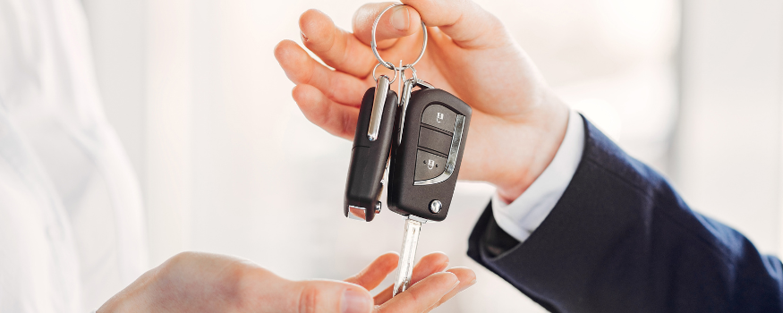 Autohändler übergibt Autoschlüssel an Kundin – symbolisches Bild für den Verkauf von Gebrauchtwagen, bei dem häufig die Differenzbesteuerung zur Anwendung kommt.