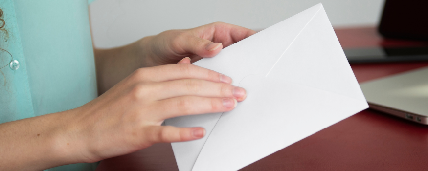 Eine Person hält einen weißen Briefumschlag in den Händen, bereit, ihn zu öffnen. Das Bild symbolisiert den Erhalt einer offiziellen Unbedenklichkeitsbescheinigung vom Finanzamt, der Krankenkasse oder der Berufsgenossenschaft als Nachweis der Zuverlässigkeit.